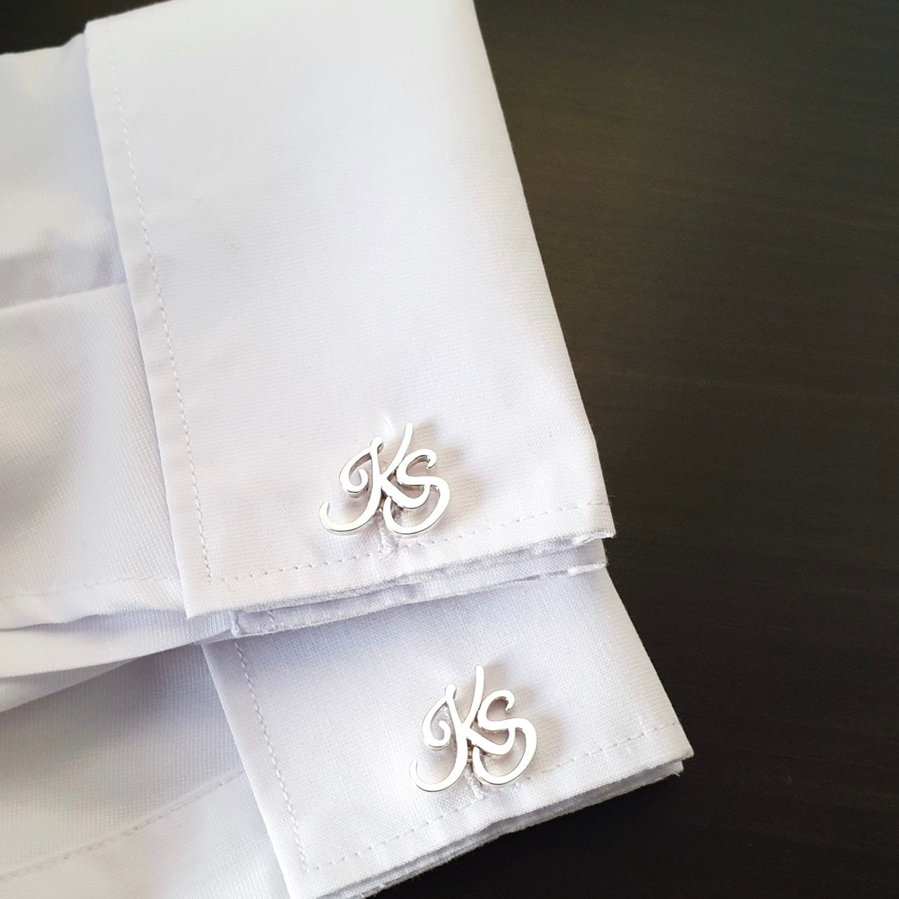 Customized cufflinks with cursive initials.