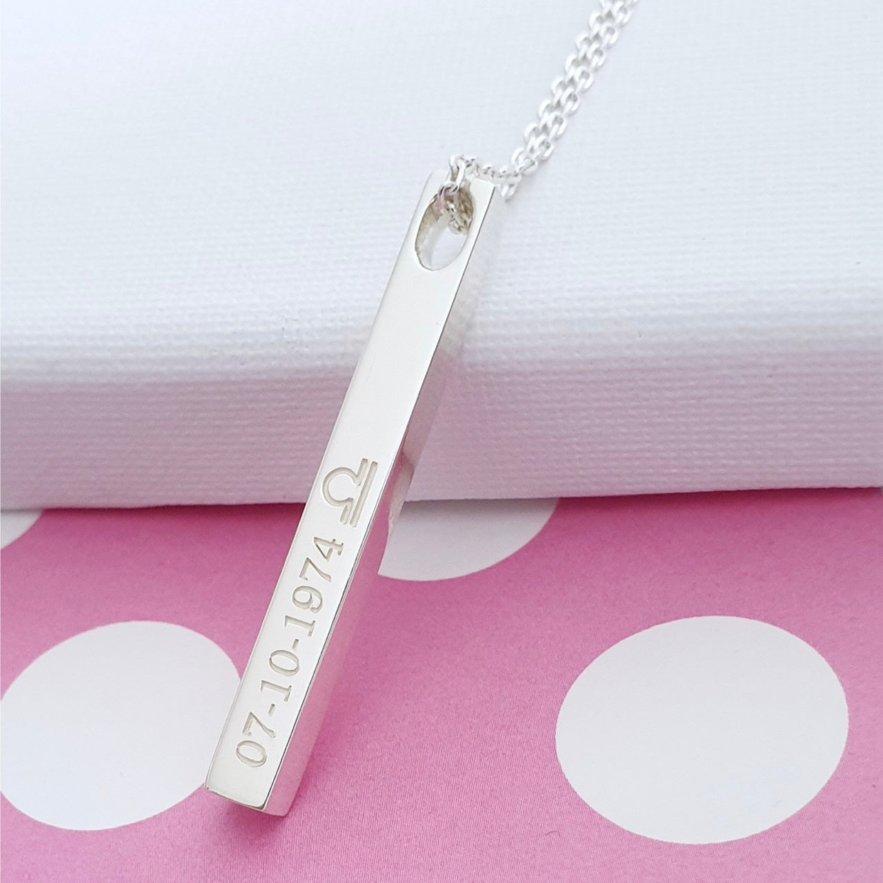 A silver square bar necklace with engraved text on all four sides. a perfect gift for girl on her birthday